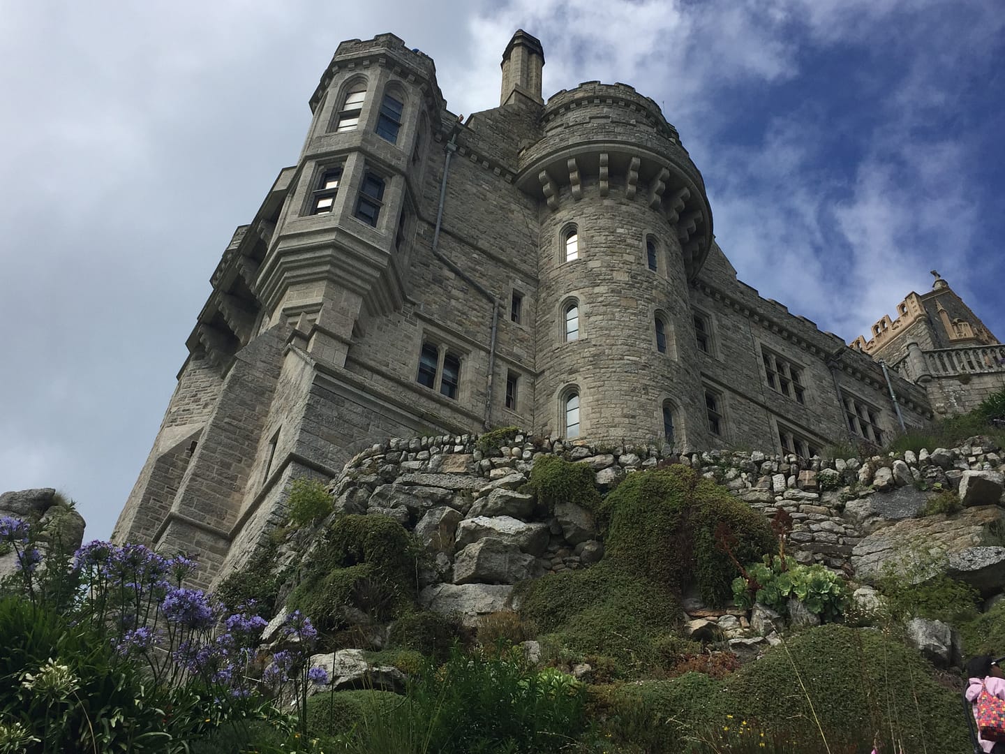 The castle at the top of St Michael's Mount seen from immediately below and looming against a cloudy sky.